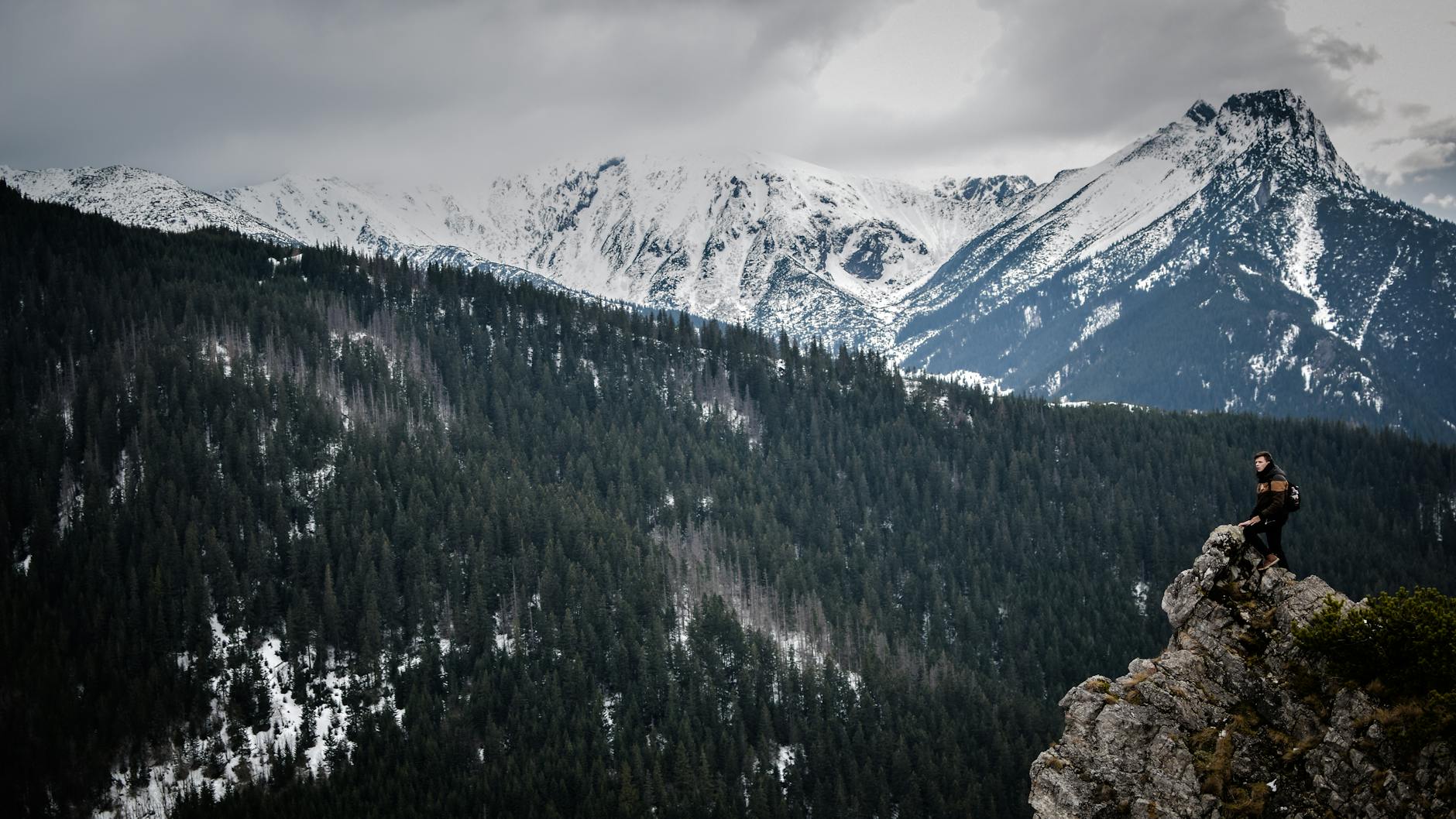 Podróżnik na skalnym klifie z widokiem na ośnieżone polskie góry