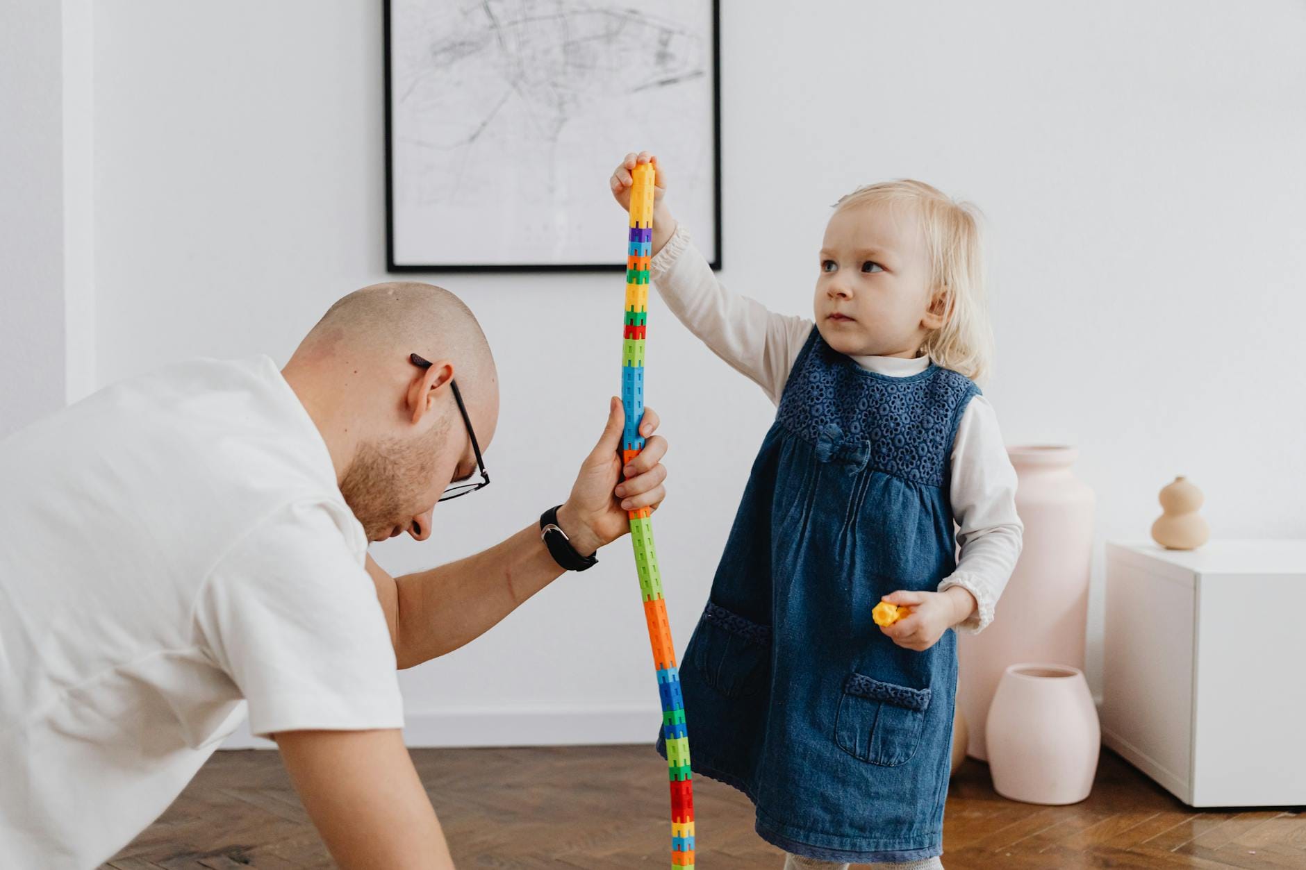 Tata bawi się z córką, budując kolorową wieżę z klocków