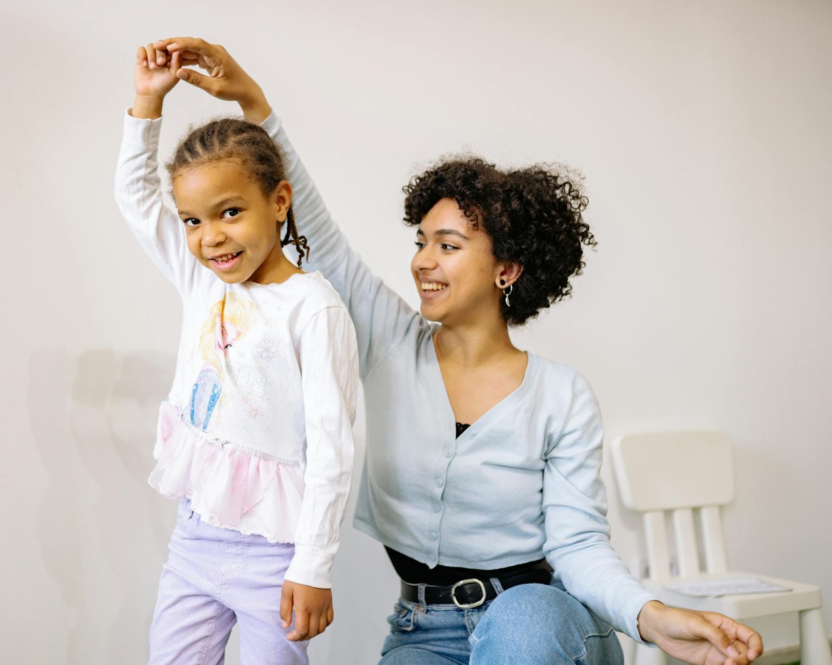 Uśmiechnięta mama tuląca córkę w domu przed pójściem do przedszkola